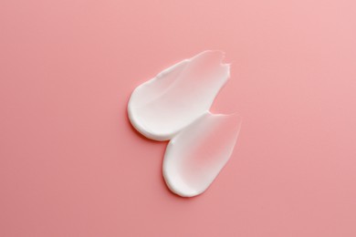 Sample facial cream on pink background, top view