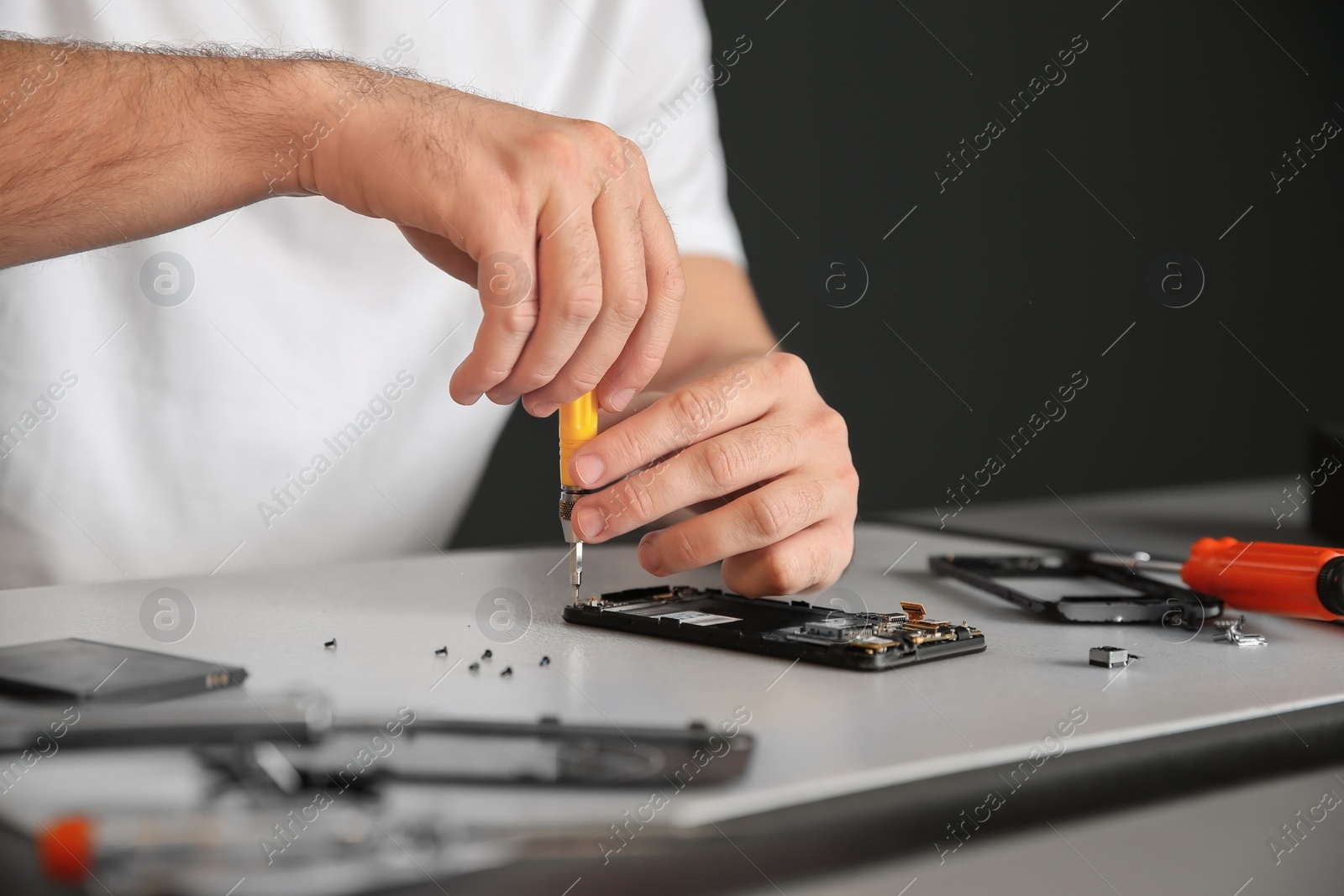 Photo of Technician repairing mobile phone at table, closeup