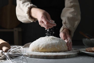 Photo of Making dough. Woman adding flour at grey table, closeup