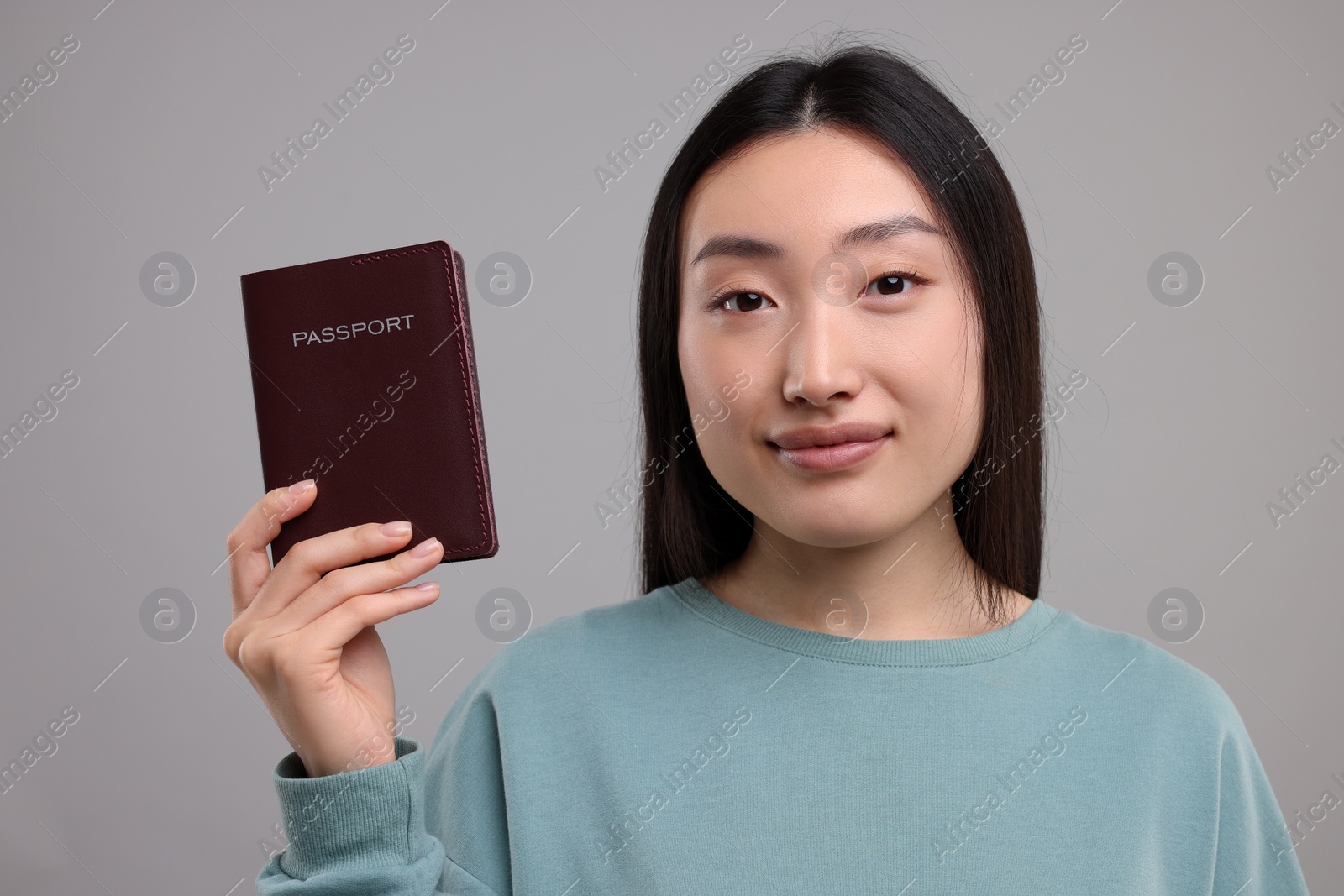 Photo of Immigration. Woman with passport on grey background