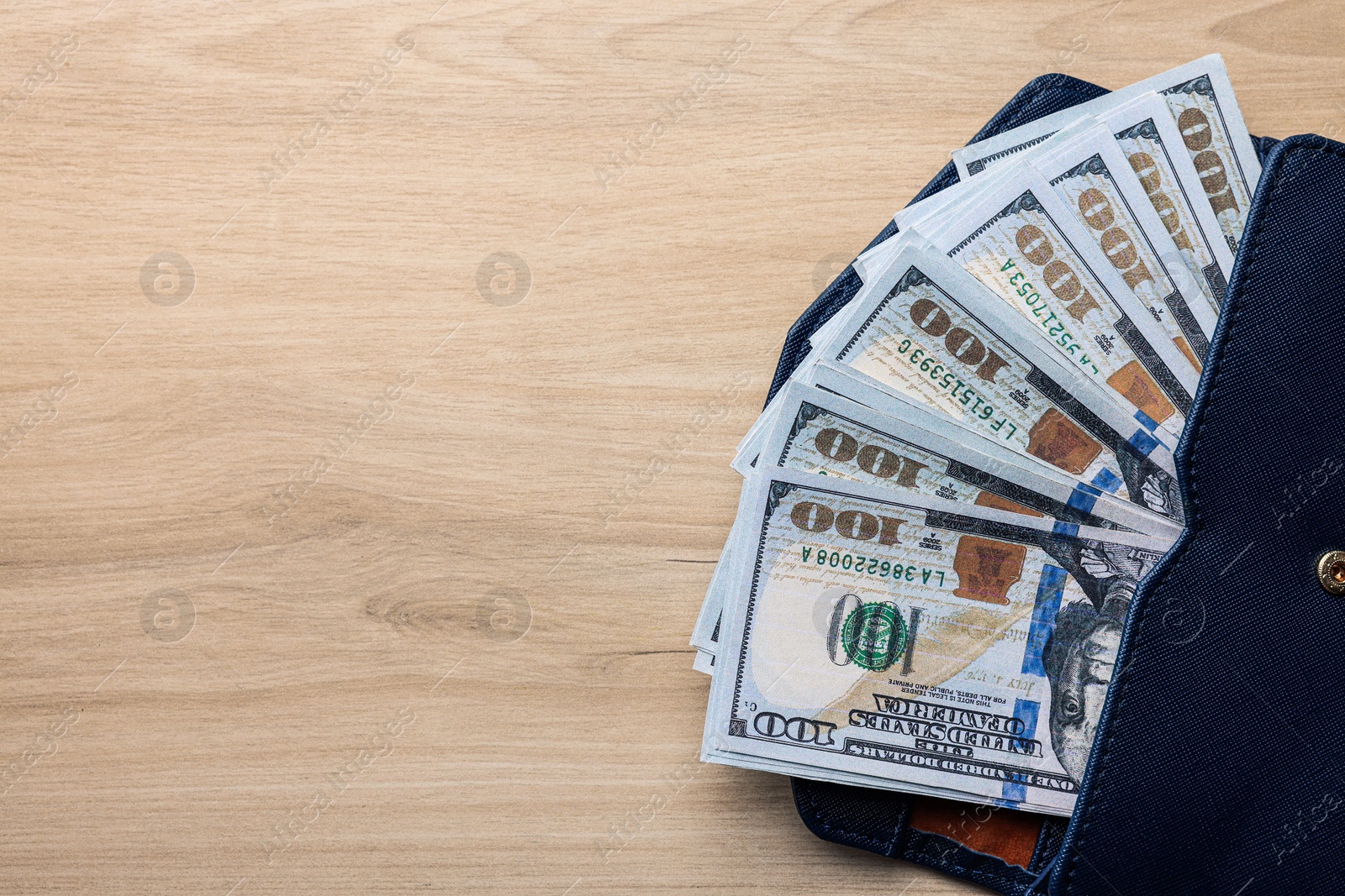 Photo of Dollar banknotes in wallet on wooden table, top view with space for text. Money exchange