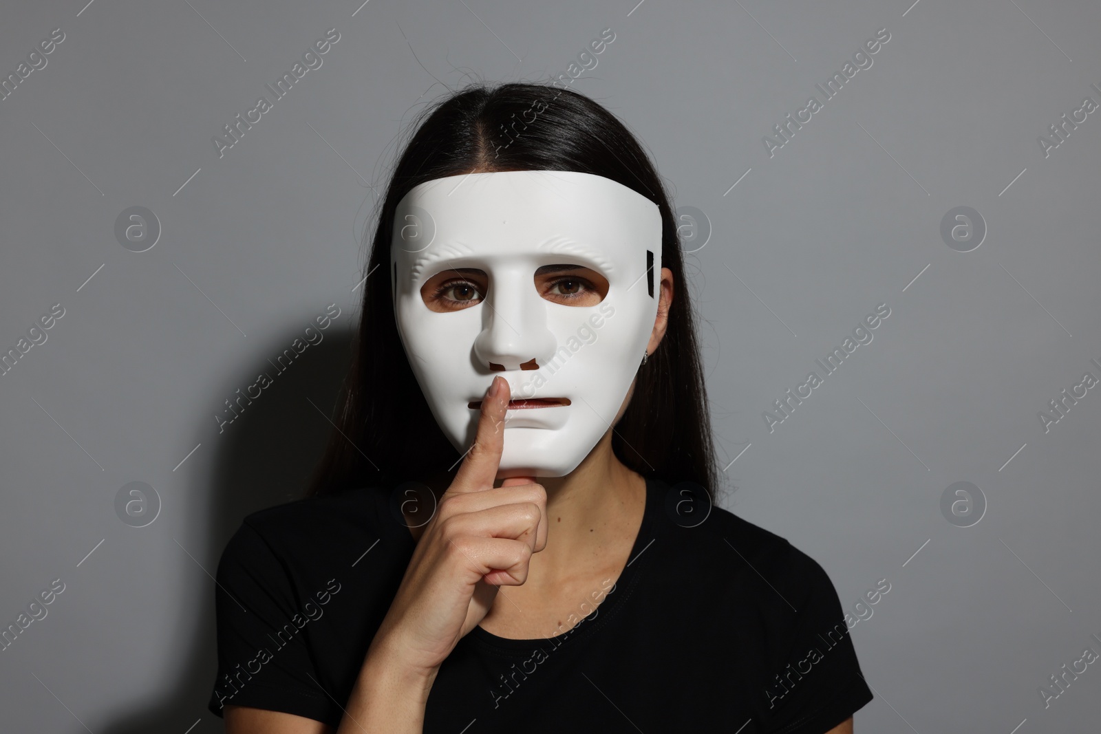 Photo of Multiple personality concept. Woman in mask on grey background