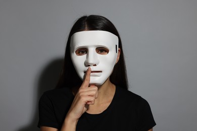 Photo of Multiple personality concept. Woman in mask on grey background