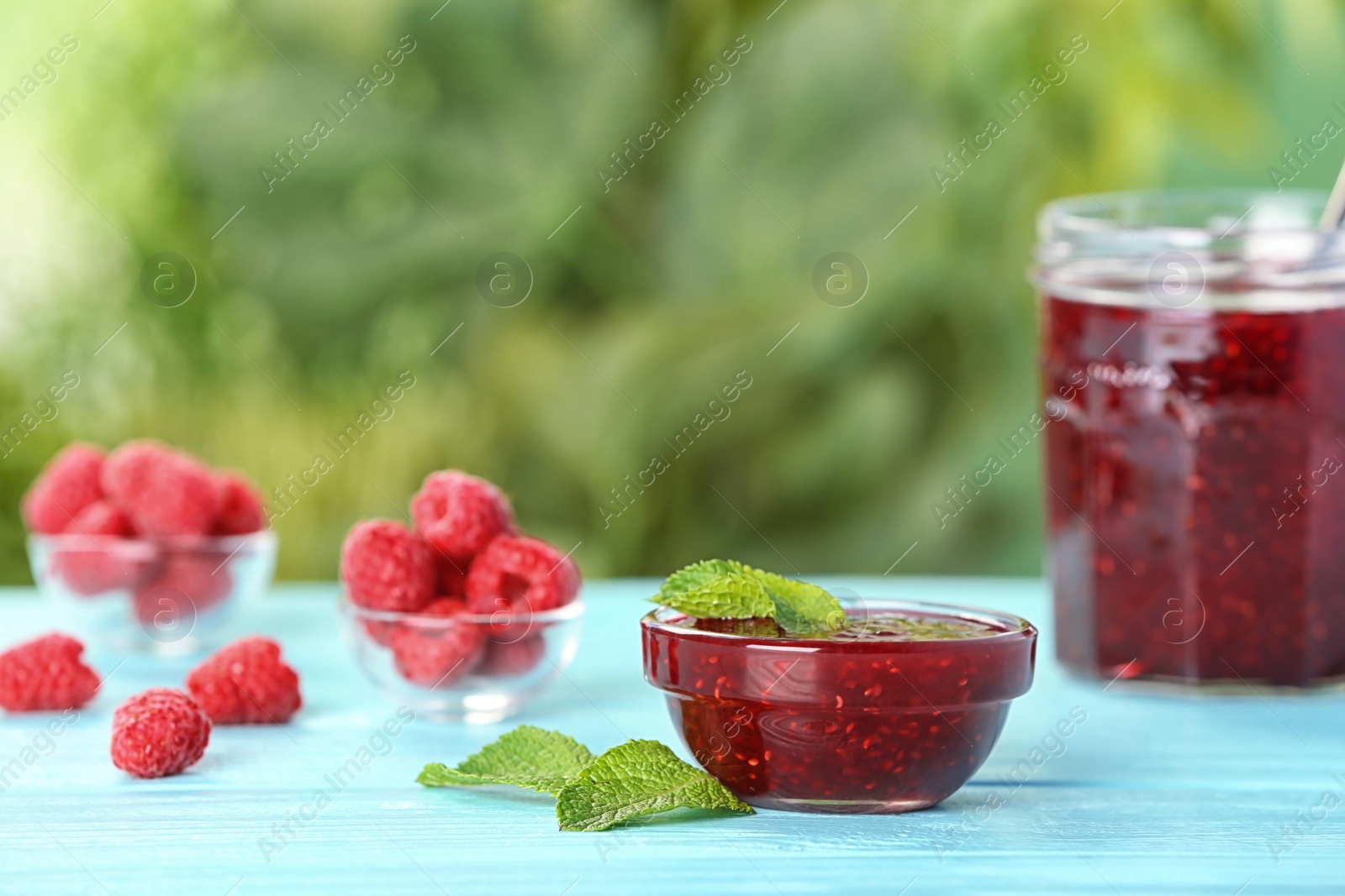 Photo of Bowl with raspberry jam on table against blurred background