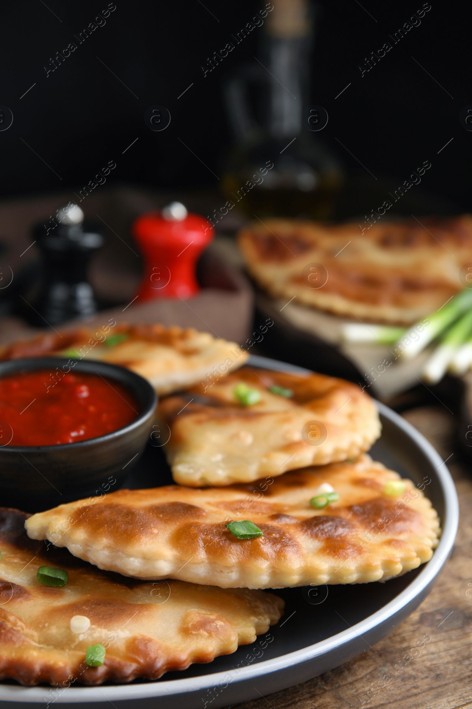 Photo of Delicious fried chebureki with ketchup on wooden table, closeup