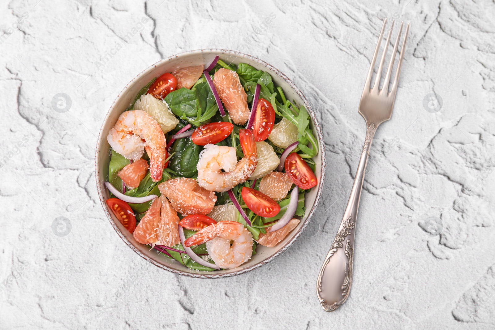 Photo of Delicious pomelo salad with shrimps served on white textured table, flat lay