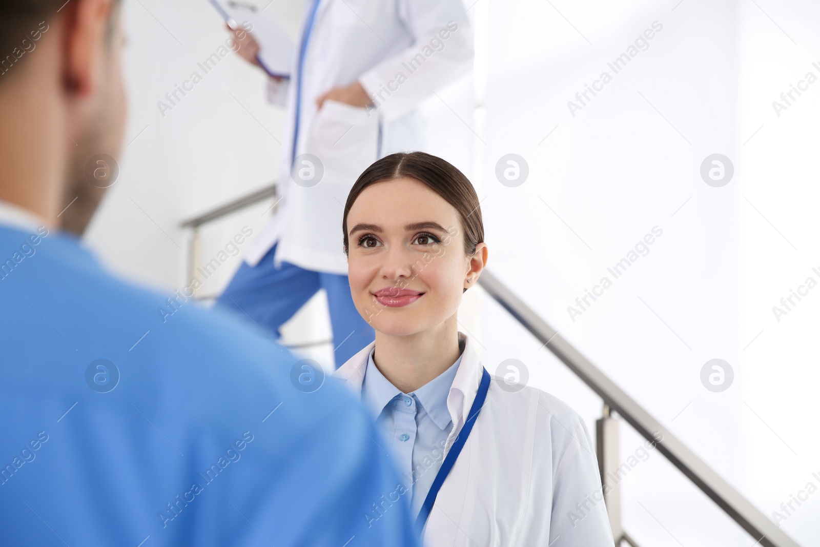 Photo of Female doctor talking to colleague on staircase in clinic