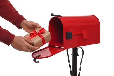 Photo of Man putting Christmas gift into mailbox on white background, closeup. Sending present by mail