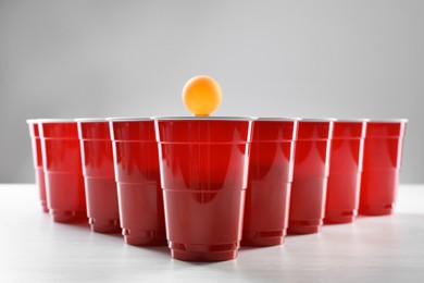 Plastic cups and ball for beer pong on white table