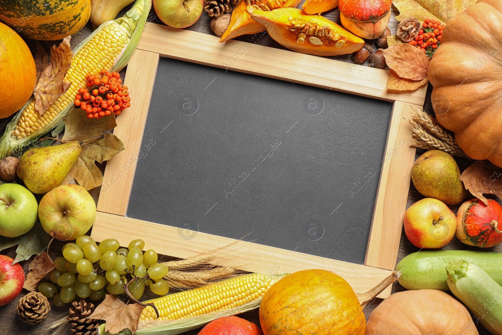 Photo of Chalkboard with space for text, autumn vegetables and fruits on wooden background, flat lay. Happy Thanksgiving day