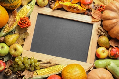 Chalkboard with space for text, autumn vegetables and fruits on wooden background, flat lay. Happy Thanksgiving day