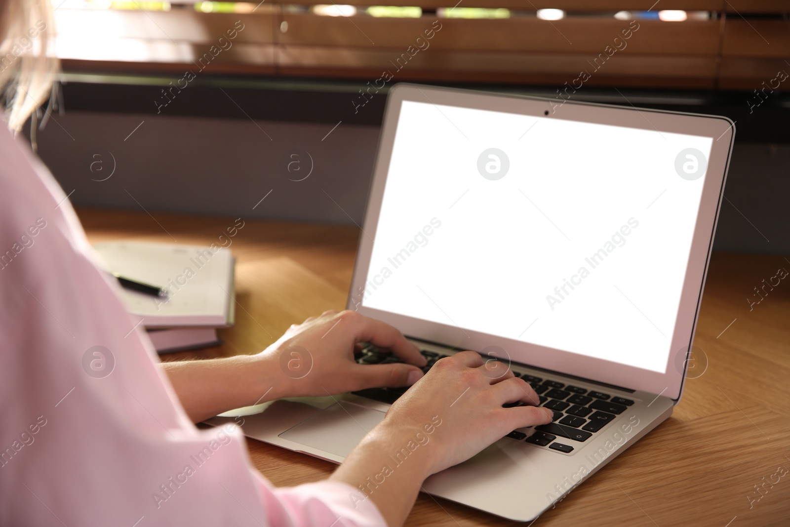 Photo of Woman using modern laptop at wooden table indoors, closeup