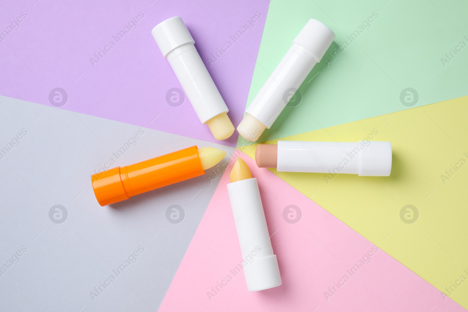 Photo of Hygienic lipsticks on color background, flat lay