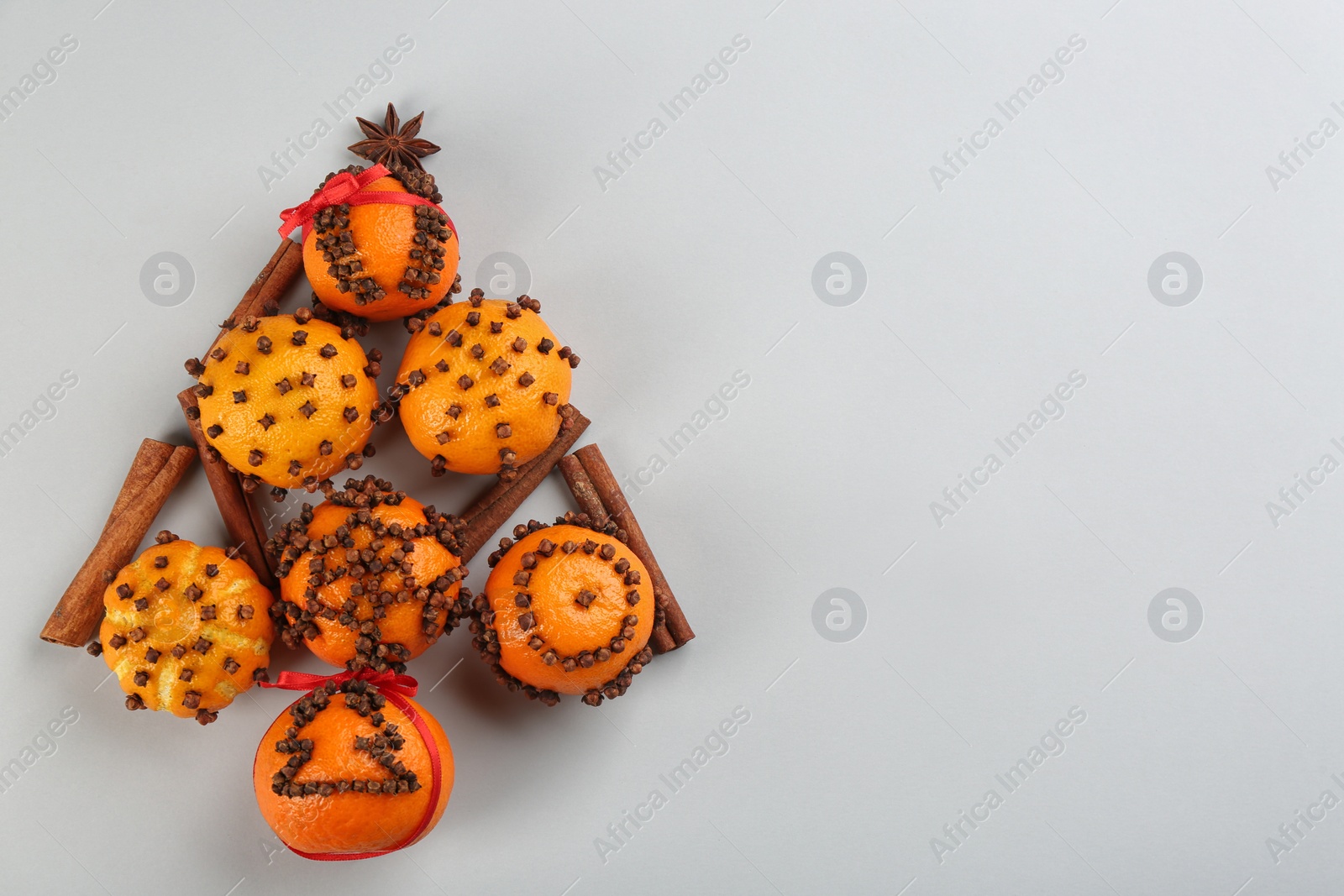 Photo of Christmas tree shape made of fresh tangerines and spices on light grey background, flat lay. Space for text