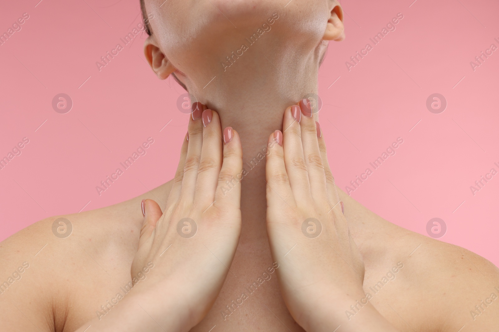 Photo of Woman touching her neck on pink background, closeup