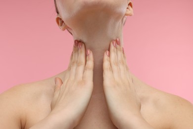 Photo of Woman touching her neck on pink background, closeup