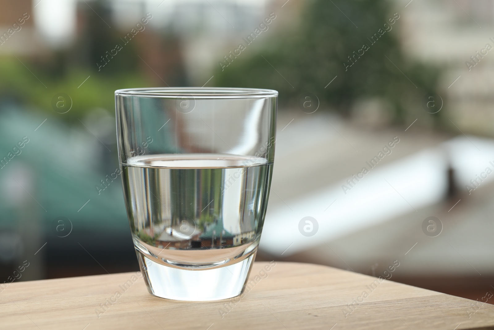 Photo of Glass of pure water on wooden table against blurred background, space for text