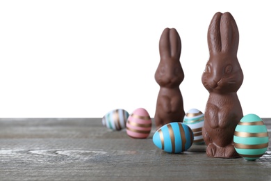 Photo of Chocolate Easter bunnies and eggs on grey wooden table against white background. Space for text