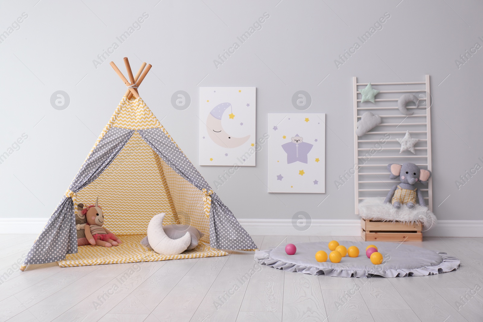 Photo of Stylish child's room interior with adorable paintings and play tent