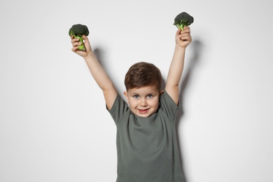 Photo of Adorable little boy with broccoli on white background