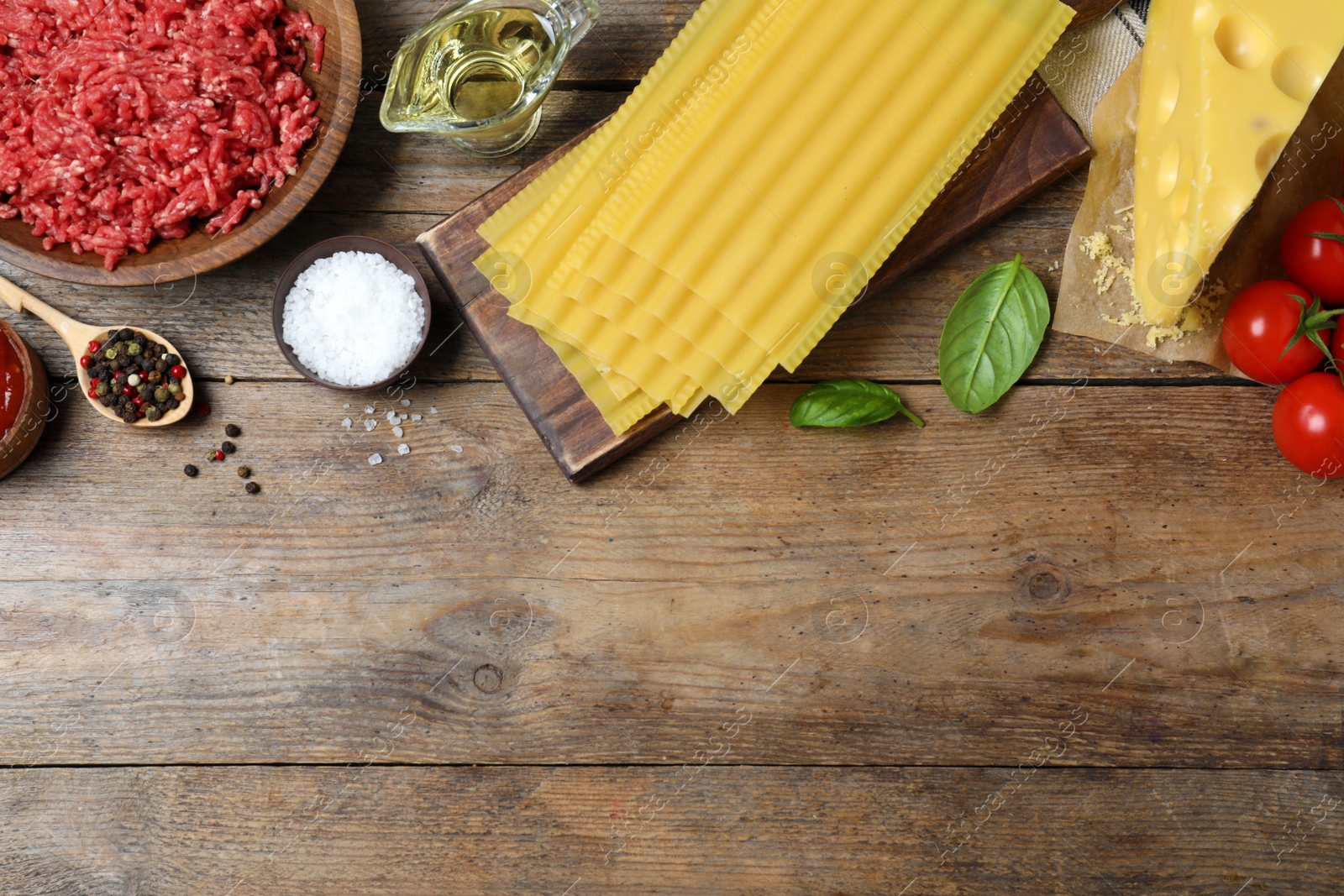 Photo of Fresh lasagna ingredients on wooden table, flat lay. Space for text