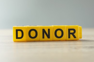 Word Donor made of yellow cubes on wooden table