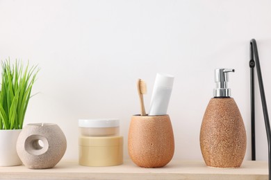 Photo of Different bath accessories, personal care products and artificial plant on wooden shelf