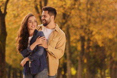 Photo of Beautiful couple spending time together in autumn park, space for text