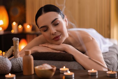 Photo of Spa therapy. Beautiful young woman lying on massage table in salon