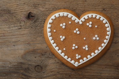 Photo of Heart shaped Christmas cookie on wooden table, top view. Space for text