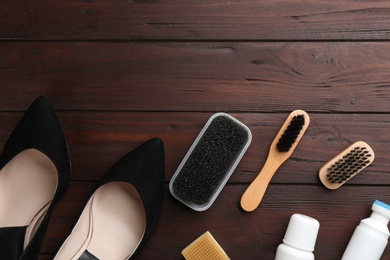 Photo of Stylish footwear with shoe care accessories on brown wooden table, flat lay. Space for text