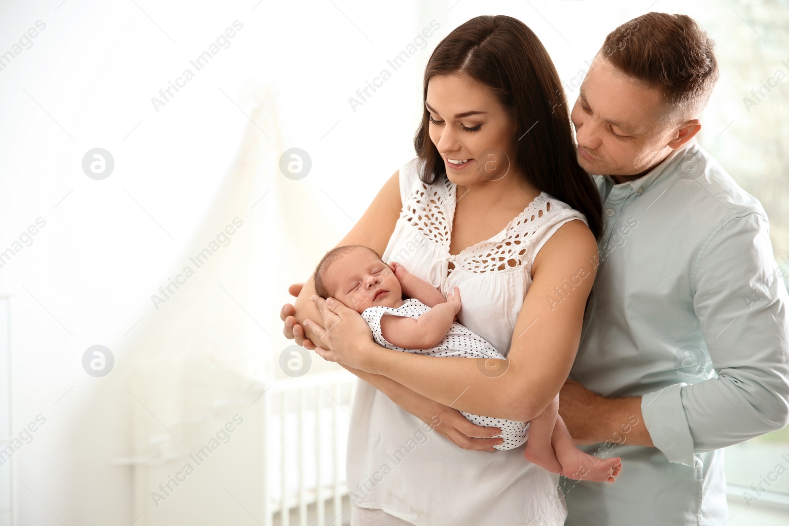 Photo of Happy couple with their newborn baby at home. Space for text
