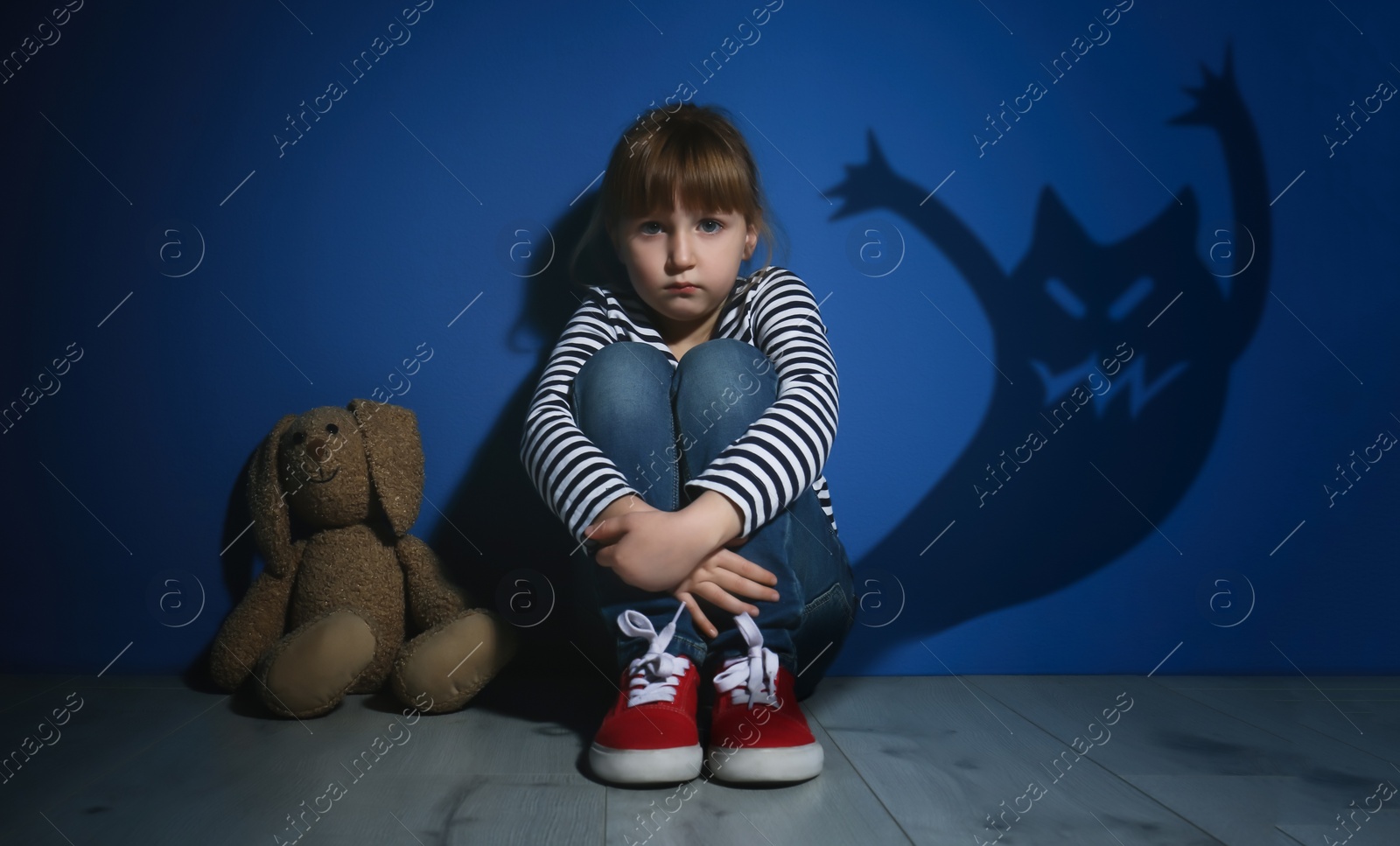 Image of Scared little girl suffering from sciophobia and phantom behind her. Irrational fear of shadows