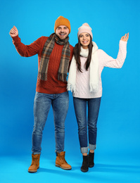 Happy young couple in warm clothes on blue background. Winter vacation