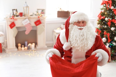 Authentic Santa Claus with bag of gifts indoors