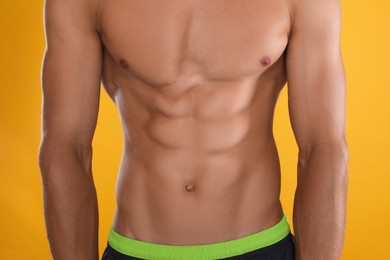 Photo of Shirtless man with slim body on yellow background, closeup
