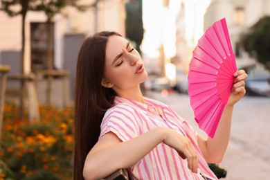 Photo of Woman with hand fan suffering from heat outdoors