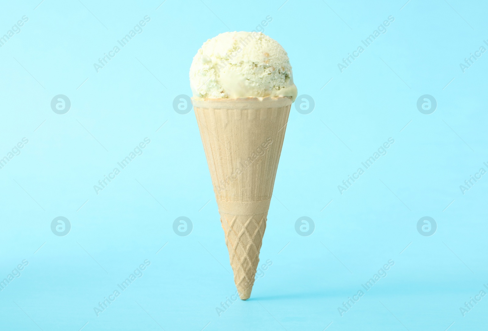 Photo of Delicious ice cream in waffle cone on light blue background