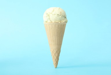 Delicious ice cream in waffle cone on light blue background