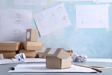 Photo of Creating packaging design. Drawings, boxes and stationery on blue textured table, closeup