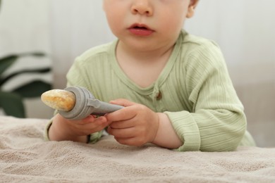 Photo of Cute baby girl with nibbler near bed at home