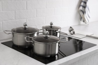 Photo of Set of new clean cookware on cooktop in kitchen