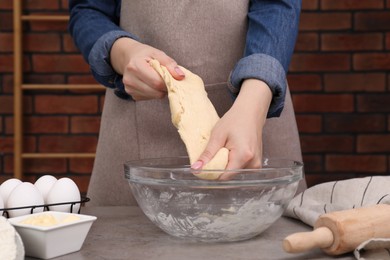 Photo of Making tasty baklava. Woman kneading raw dough at grey table, closeup