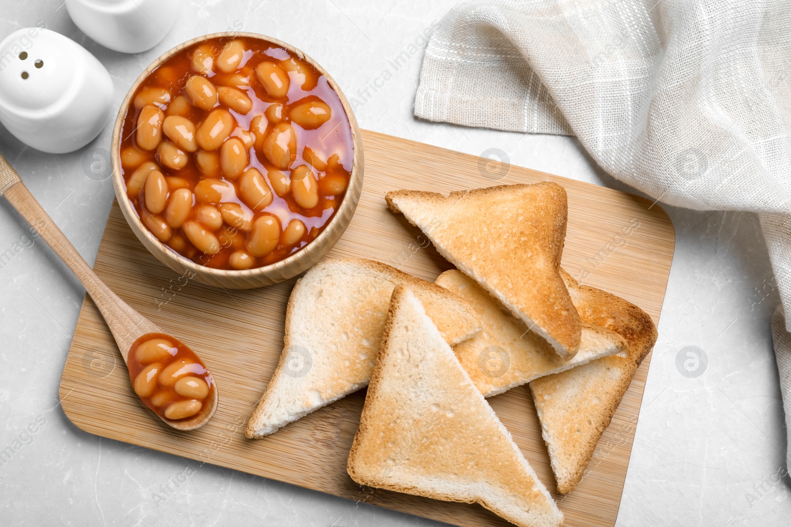 Photo of Toasts and delicious canned beans on white table, flat lay