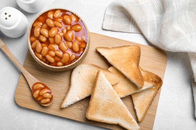 Photo of Toasts and delicious canned beans on white table, flat lay