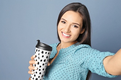 Young beautiful woman taking selfie against grey background