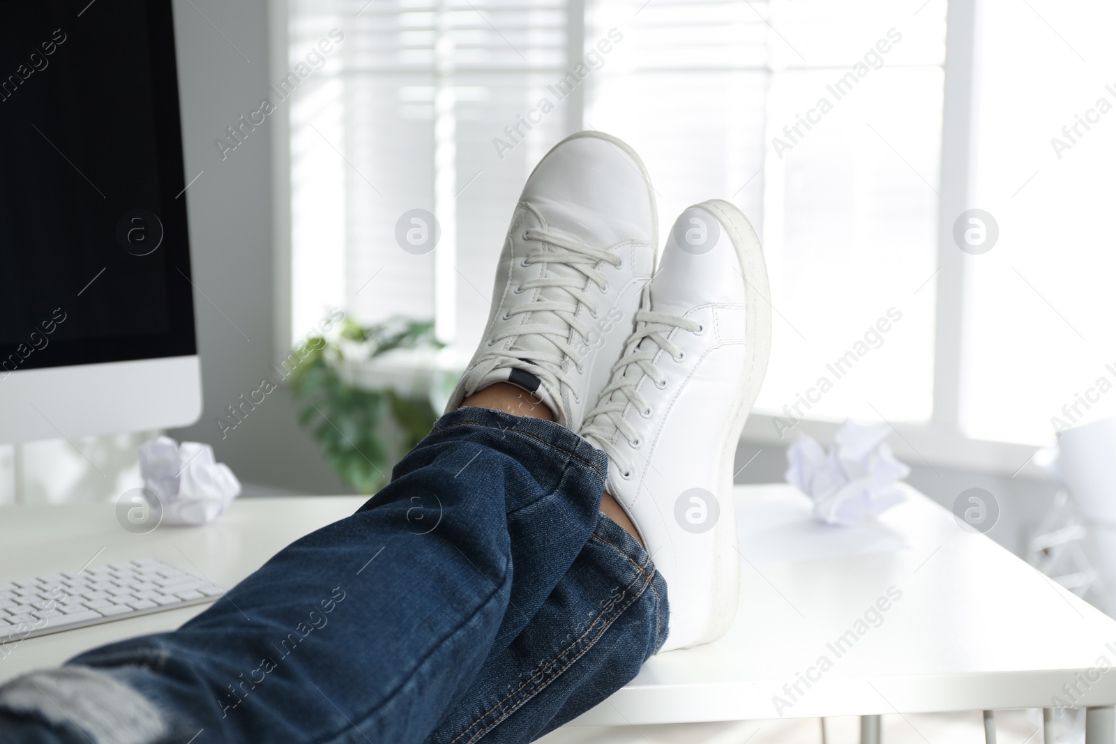 Photo of Lazy office employee resting with feet on desk in office, closeup