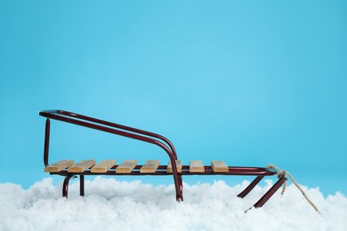 Photo of Sleigh and artificial snow on light blue background. Winter outdoor activity