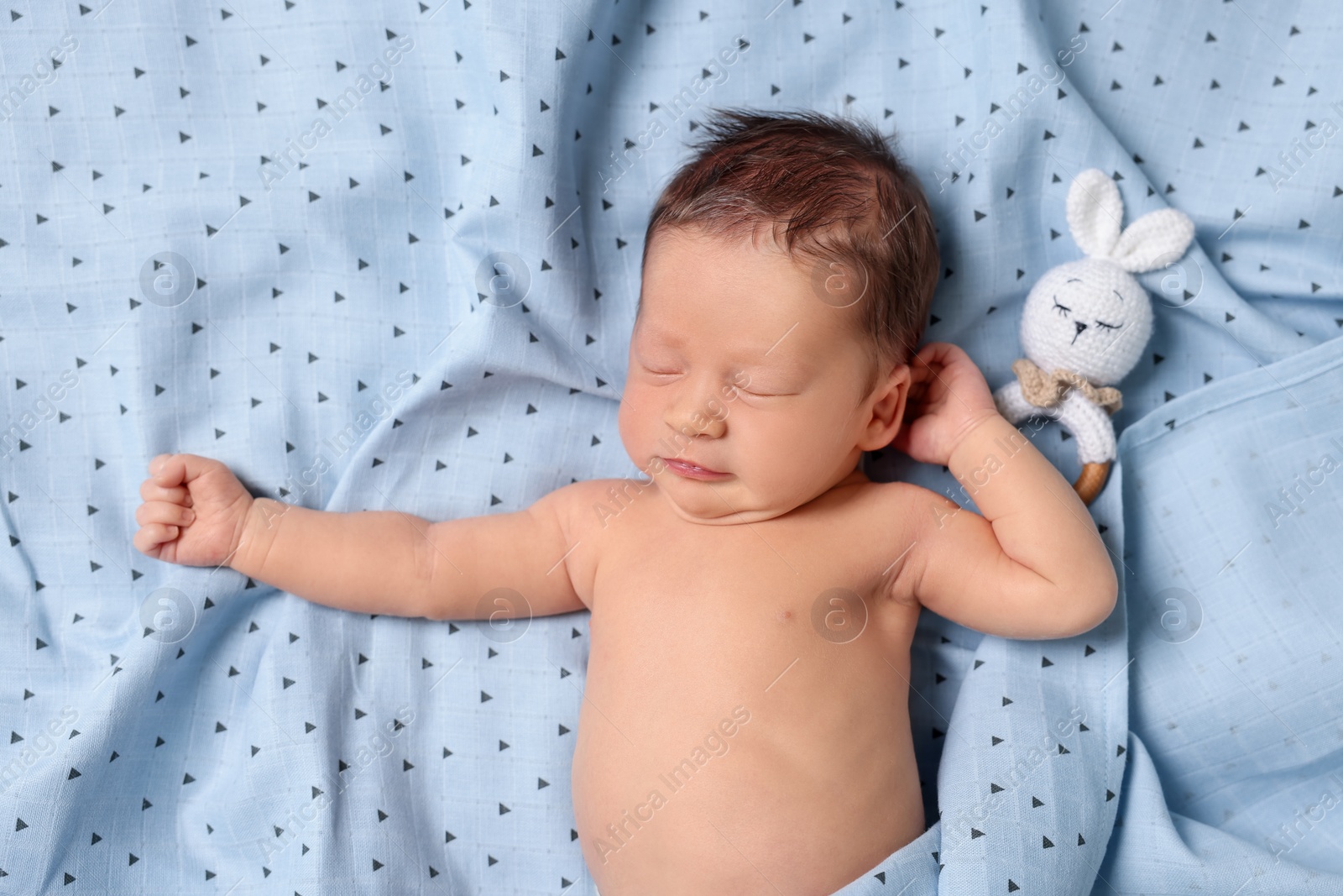 Photo of Cute newborn baby with toy bunny sleeping on bed, top view