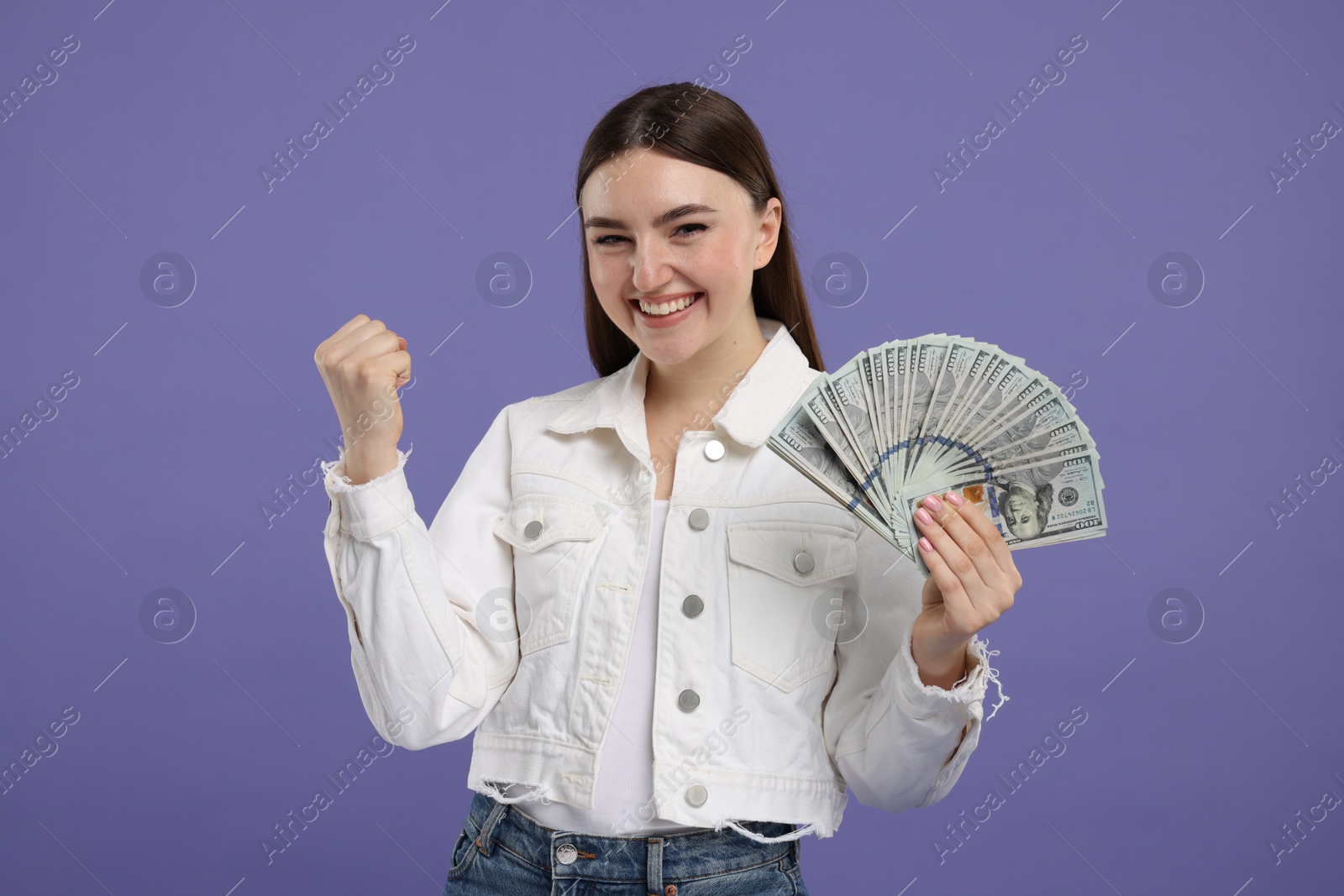 Photo of Excited woman with dollar banknotes on purple background